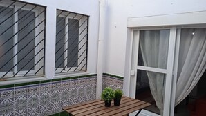 A small patio area with a wooden table and two potted plants. - San Fernando, Cadiz  (San Fernando)
