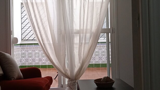 A room with a red sofa, a black table, and sheer curtains. - San Fernando, Cadiz  (San Fernando)