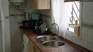 A compact kitchen with a washing machine, microwave, sink, and stove. - San Fernando, Cadiz  (San Fernando)