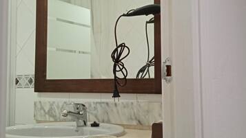 Een bad/douchecombinatie, een haardroger, een bidet, handdoeken