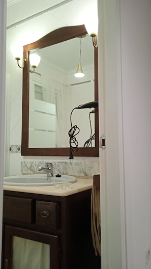 A bathroom with a large mirror, a sink, a towel rack, and a door.