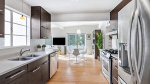 A modern kitchen with stainless steel appliances, a large window, and a dining area with a white table and chairs. - ICONIC MID-CENTURY MODERN  “HAVER HOME” (Scottsdale)