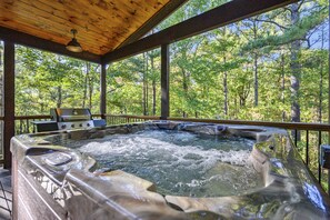 Ein Whirlpool mit Holzterrasse und Blick auf einen Wald.