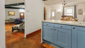 A kitchen with blue cabinets, a wooden bench, and a stone wall. - Victorian style home, where shabby chic meets the beach (Torquay)