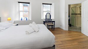 A hotel room with a large bed, a desk with a mirror, and a shower area. - Victorian style home, where shabby chic meets the beach (Torquay)