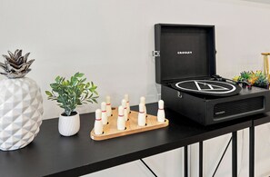 A black speaker cabinet with a logo, a white potted plant, a wooden bowling pin rack, and a decorative metal piece on a black table.