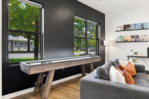A modern living room with a bench, a grey sofa, and a wall with framed pictures.