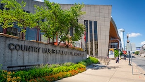 A building with a sign reading "Country Music Hall of Fame and Museum" and a landscaped area with plants and flowers.