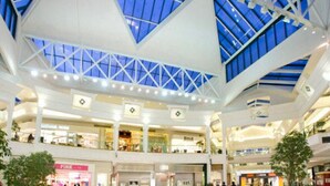 A multi-level shopping mall with a high ceiling and skylights.