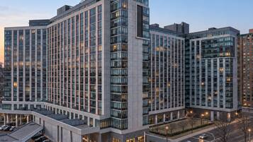 A multi-story hotel with a modern architectural design, featuring a large parking area and a well-lit entrance.
