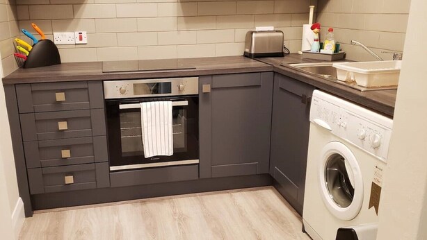 A compact kitchen with a built-in oven, a washing machine, and a toaster. - # 5 Central Killarney Apartment (KILLARNEY)