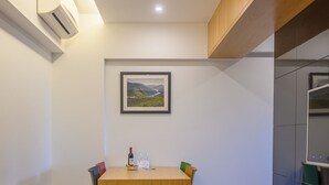 Un salon moderne avec une table à manger en bois, un canapé en cuir et un tableau représentant un paysage, accroché au mur.