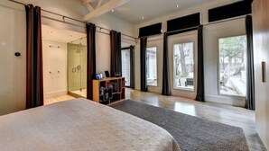 Ein geräumiges Schlafzimmer mit einem großen Bett, einem begehbaren Kleiderschrank und einer Schiebetür zu einem Balkon.