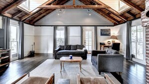 Ein geräumiges Wohnzimmer mit hohen Decken, großen Fenstern und einem gemütlichen Kamin.
