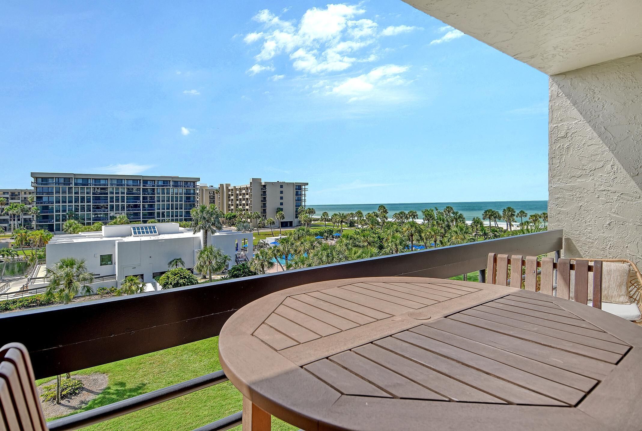 A balcony with a view of the ocean and palm trees.
