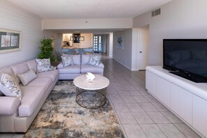 Relax in a cozy living space with a beige sofa, round coffee table, and flat-screen TV.