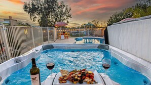 Ein Whirlpool mit Pool, umgeben von einem Zaun, und ein Sonnenuntergang im Hintergrund.