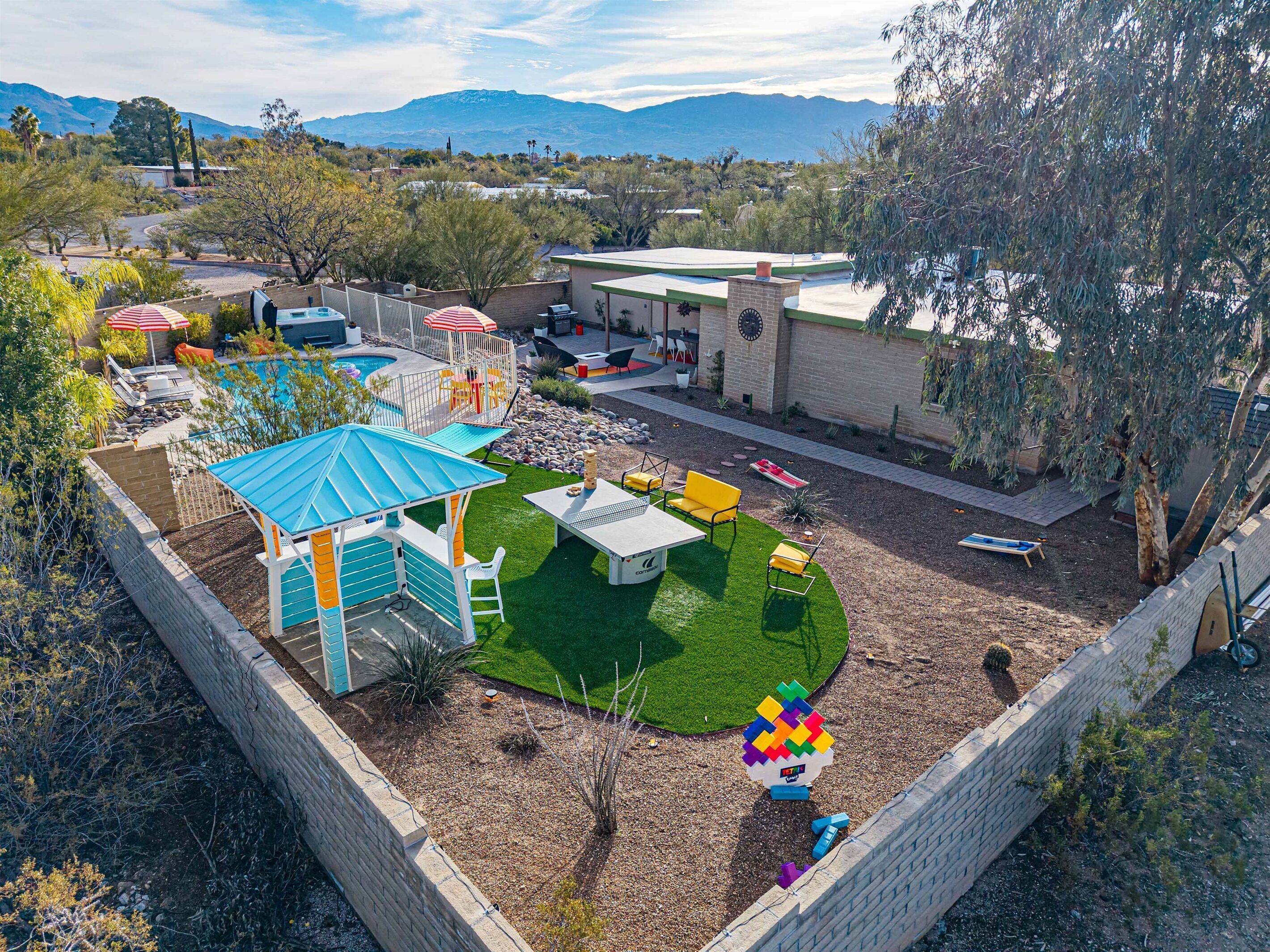 Un patio trasero cercado con piscina, zona de juegos y terraza amueblada.