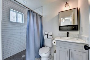 Bathroom features a white toilet, sink, and large mirror, with a shower area and window above.