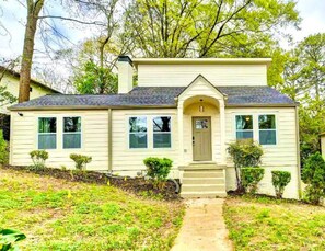 Stunning single-story home with a central entrance, two windows, and a larger window above the door.