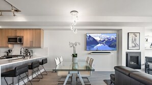 A modern kitchen with a central island, a dining area with a glass table, and a living area with a sofa. - Luxurious, Ocean View 2 Story Penthouse - Downtown - Secure Parking (Victoria)