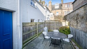A patio with a round table and four chairs, a blue door, and a wooden fence. - Superbly located St Andrews 2 bedroom apartment.  Beach and golf close by! (St Andrews)
