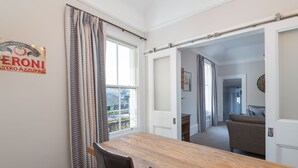 A dining area with a wooden table and chairs, a window with curtains, and a view of the outside. - Superbly located St Andrews 2 bedroom apartment.  Beach and golf close by! (St Andrews)