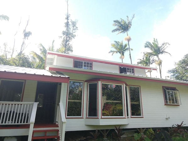 A two-story house with a red and white exterior, large windows, and a porch with a white railing.