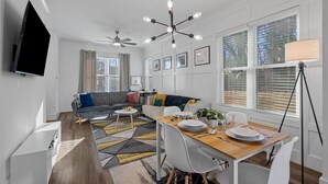 A modern living room with a sofa, dining table, and ceiling fan.