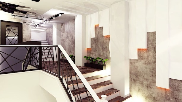 Una escalera moderna con un diseño geométrico en la barandilla, que conduce a un rellano con una planta y un diseño geométrico en la pared.