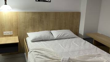 A neatly made bed with white linens in a room with wooden headboard and nightstands.