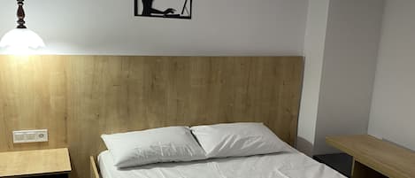 A neatly made bed with white linens in a room with wooden headboard and nightstands.