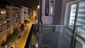 Vista nocturna desde un balcón con vista a una calle con coches aparcados y edificios.