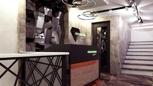 Un área de recepción de diseño moderno, con un mostrador de recepción, un patrón geométrico en la pared y una escalera al fondo.
