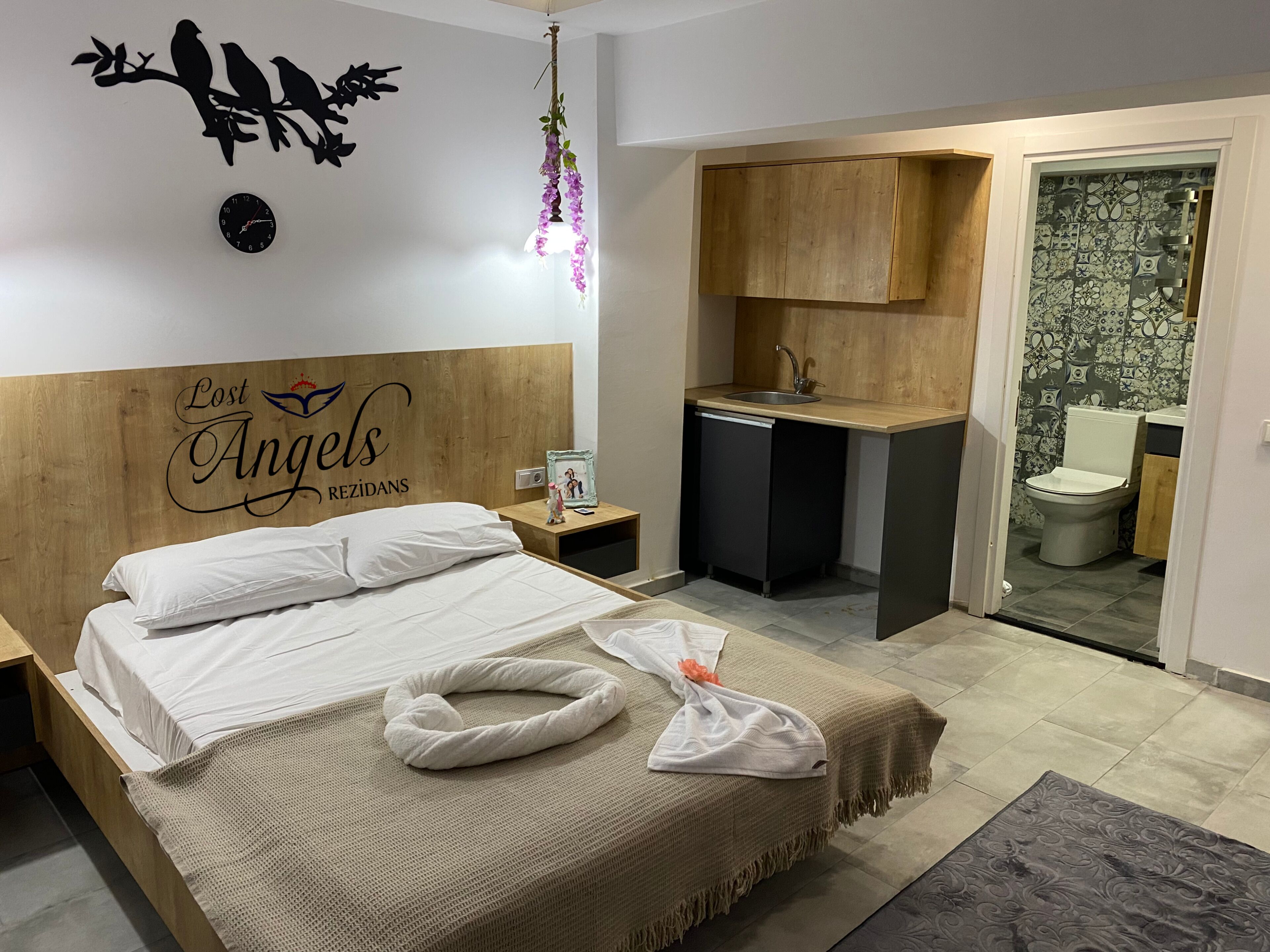 A hotel room with a bed, a small desk with a sink, and a bathroom visible through an open door.