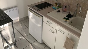 A compact kitchen with white cabinets, a built-in dishwasher, a sink with a faucet, and a small countertop.