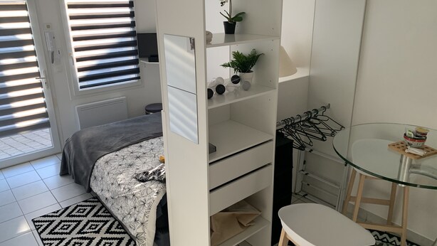 A compact bedroom with a bed, a desk, a chair, and a small table.