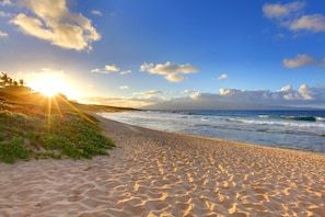 A beach with a clear sky and sunlight reflecting off the sand.