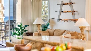 A modern living room with a sofa, two lamps, a coffee table, and a decorative wall piece. - Spacious OceanFront 2BD w Pool AC-Royal Kahana 701 (Lahaina)