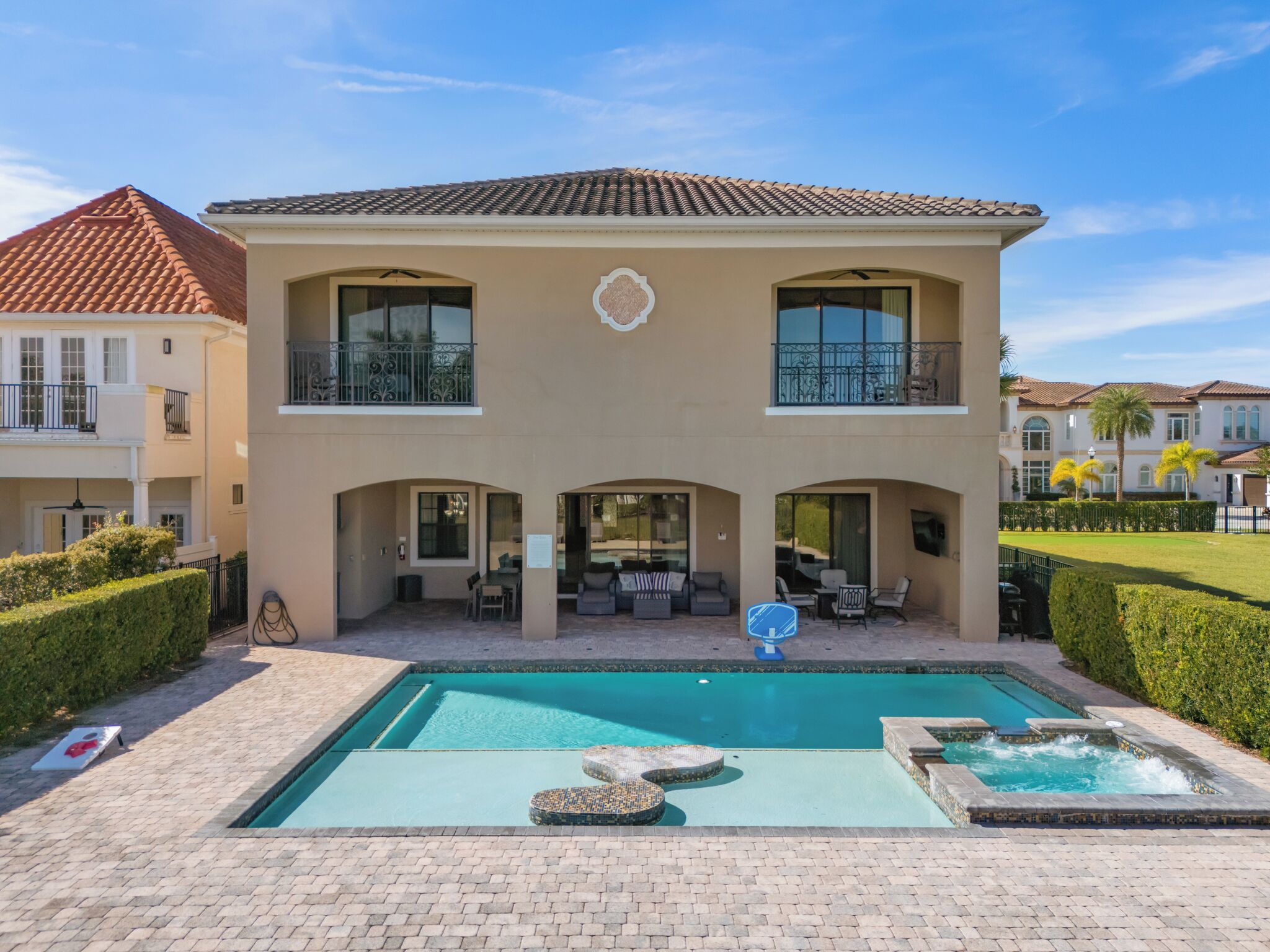 A two-story house with a swimming pool, outdoor seating, and a well-maintained garden.