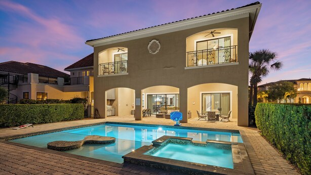 Une maison à deux étages avec une piscine, un patio doté de meubles d’extérieur et un jardin bien entretenu.