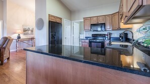 A modern kitchen with wooden cabinets, a black refrigerator, and a stainless steel sink.