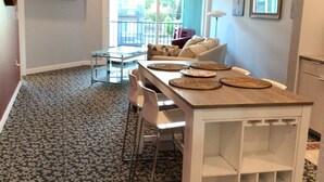 Un espace de vie compact comprenant un coin repas, un ventilateur de plafond, un téléviseur fixé au mur et une vue par la fenêtre.