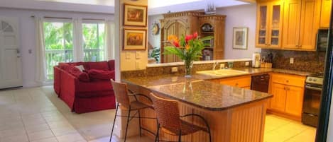 Una cocina amplia con una isla central, armarios de madera y un sofá rojo en la sala de estar.