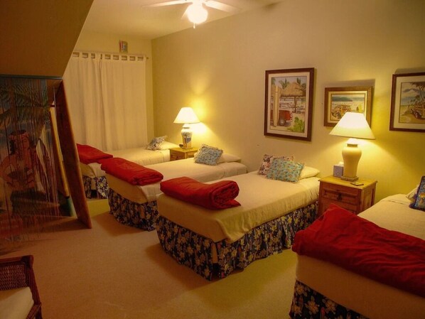 A hotel room with two beds, each with a red blanket, a nightstand with a lamp, and a painting on the wall.