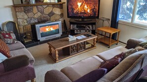 A cozy living room with a stone fireplace, a television, and a comfortable seating area.