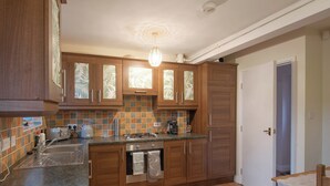 A kitchen with wooden cabinets, a tiled backsplash, and a stainless steel sink. - 2 bedroom accommodation in Oswestry (Oswestry)