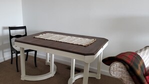 A dining table with a dark top and a white base, accompanied by a single black chair. - Historic ranch house has beautiful mountain and valley views. Weekly discounts. (Manhattan)