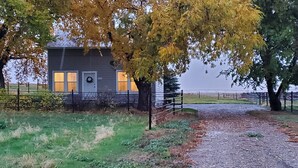 A rural house with a gravel driveway and a fenced yard. - Historic ranch house has beautiful mountain and valley views. Weekly discounts. (Manhattan)