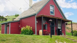 Une maison en bois rouge, avec un toit à pignon, un porche à l’avant et une cheminée.